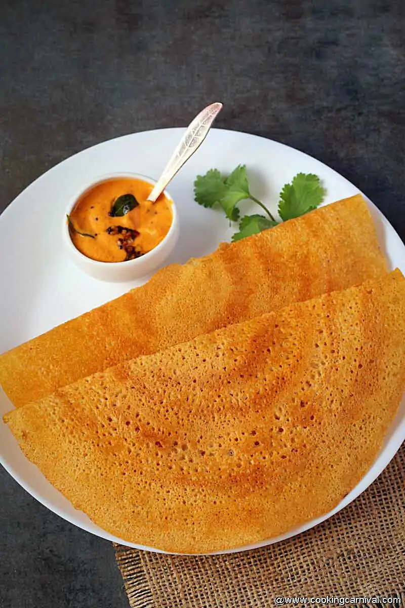 2 adai with onion chutney on a white plate with cilantro