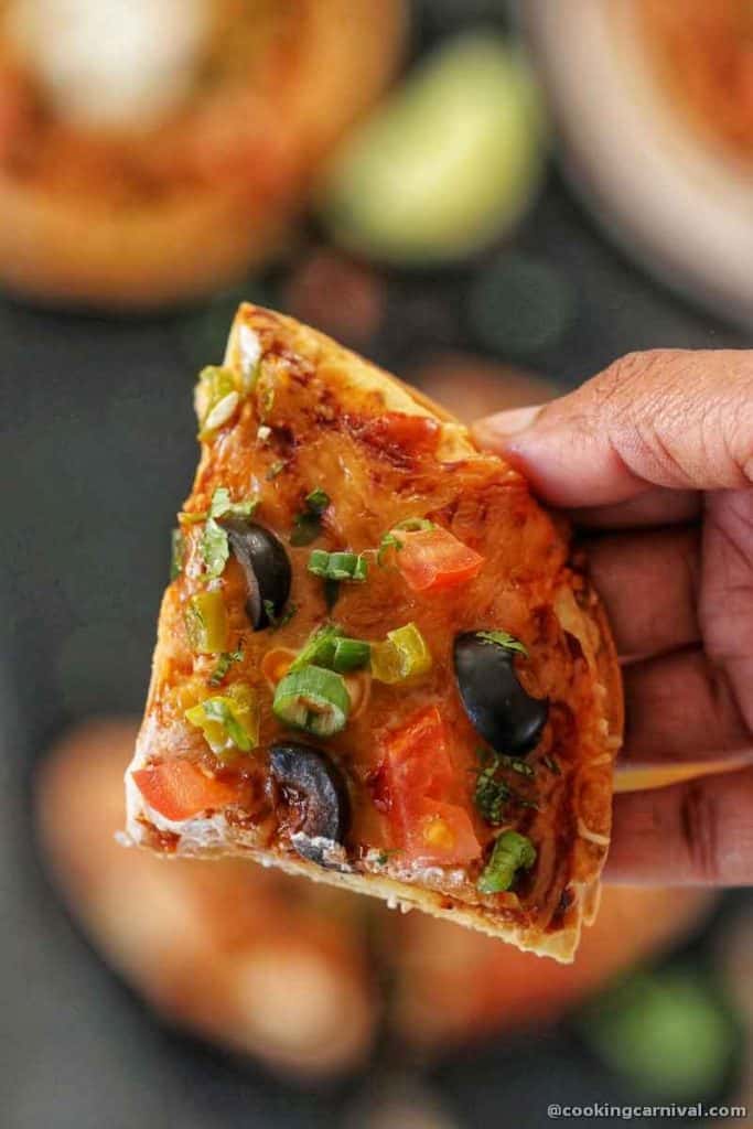 Holding a slice of homemade taco bell copycat mexican pizza