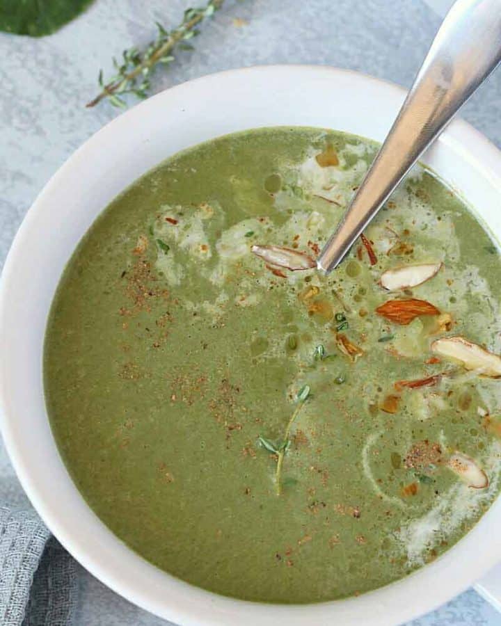 Spinach soup in white bowl with spoon
