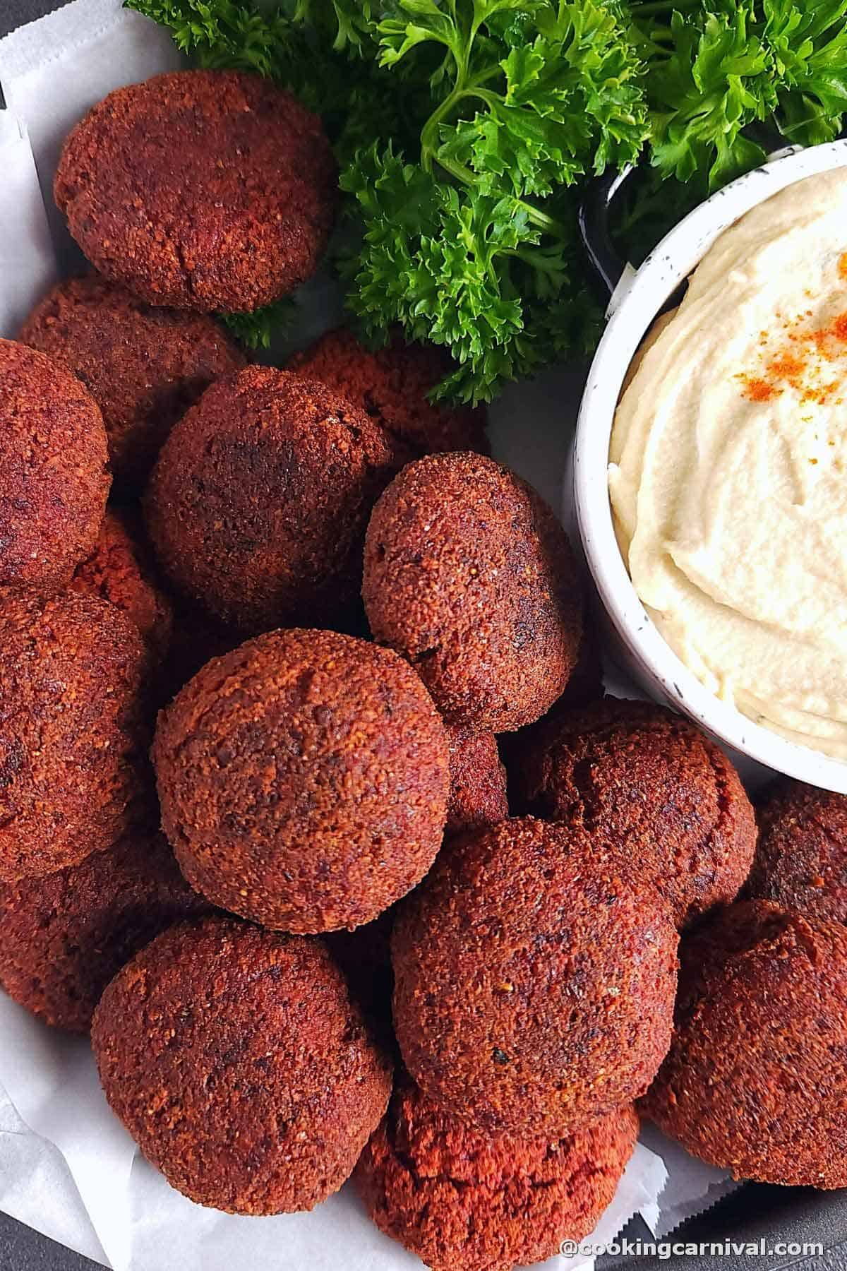 Beetroot falafel served with hummus and garnished with parsley.