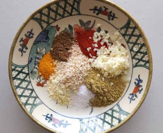 besan, coriander cumin powder, turmeric powder, garlic, salt, chili powder, peanut powder, garam masala in a bowl.