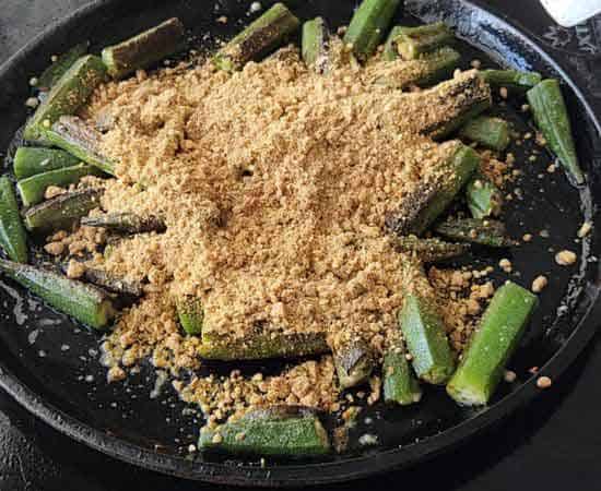 Adding besan masala in a cooked bhindi.
