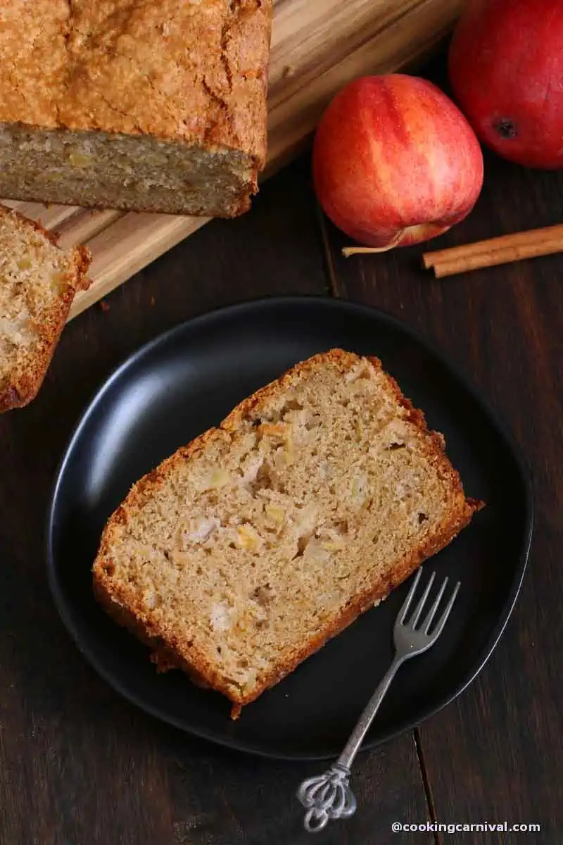 slice of apple bread on a black plate with fork.