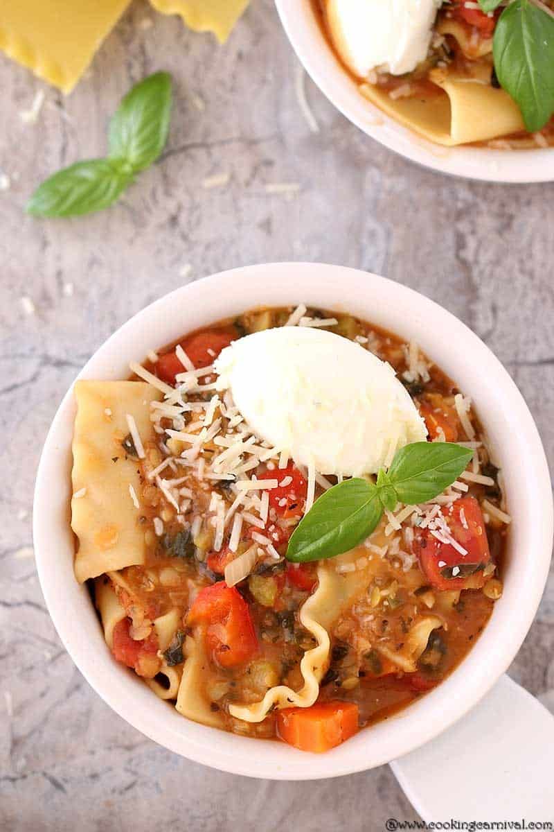 Instant Pot lasagna Soup in a white bowl with ricotta cheese and basil leaves