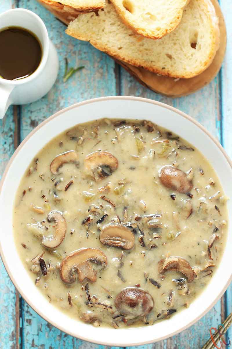  Instant Pot Wild Rice Mushroom Soup in a white bowl, olive oil and crusty no knead bread on the side