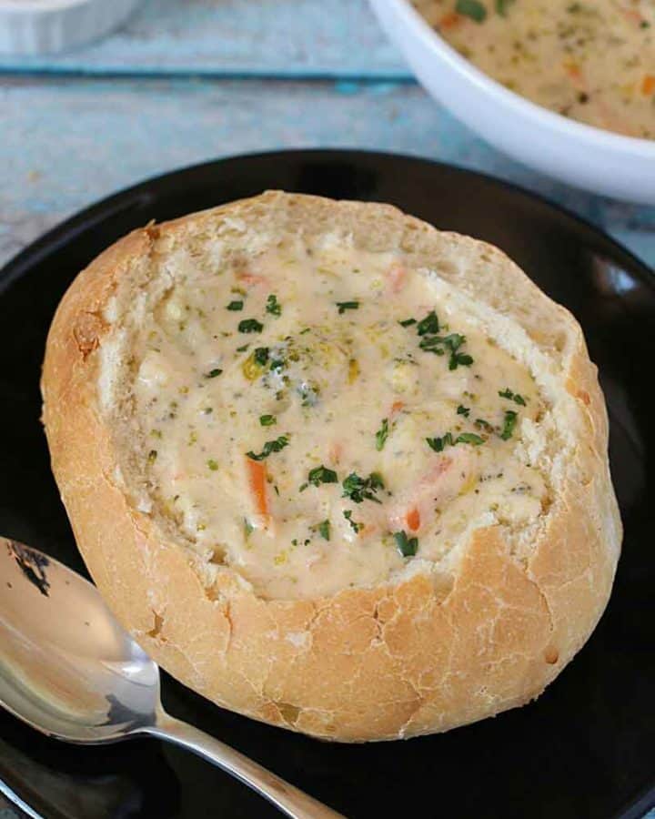 Homemade Bread bowl served with broccoli cheese soup on a black plate