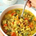 Spooning Vegetable Barley Soup from white bowl made in Instant Pot