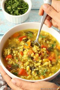 Spooning Vegetable Barley Soup from white bowl made in Instant Pot