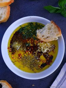 Olive oil with herbs for bread in a white bowl