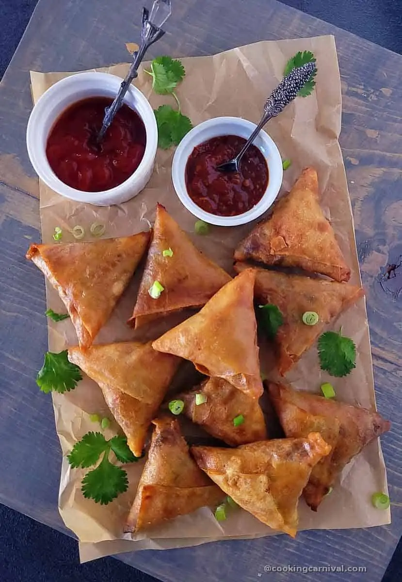 chinese samosa on gray board with ketup and schezwan sauce