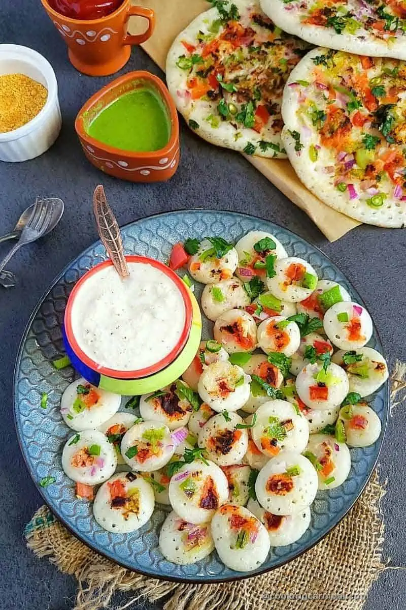 Mini uttapams in a plate with coconut chutney and green chutney.