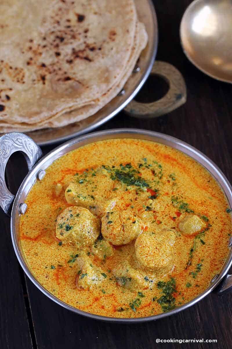 Gatte Ki Sabji - A Rajasthani dish made with gram flour, yogurt and basic Indian spices, served in a steel bowl with roti on the side.
