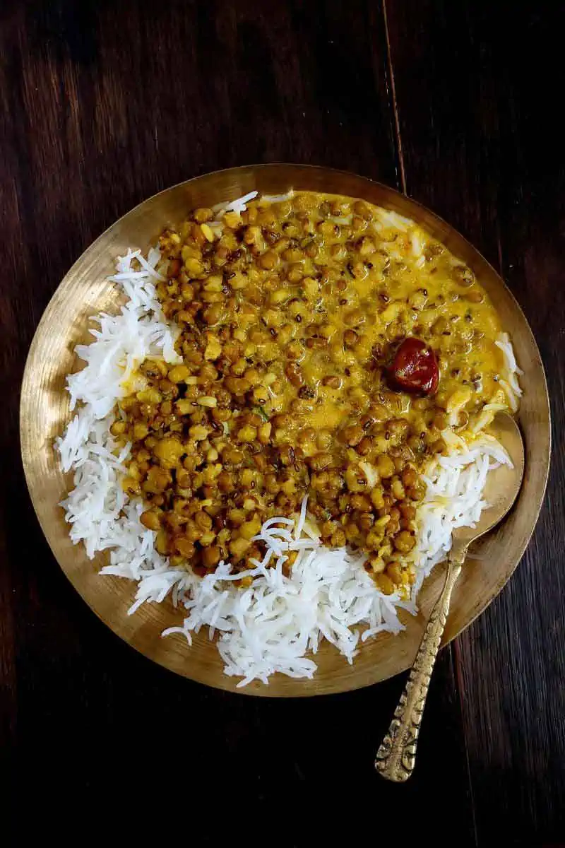 Whole moong dal served with steamed rice in a traditional kansa plate and spoon.