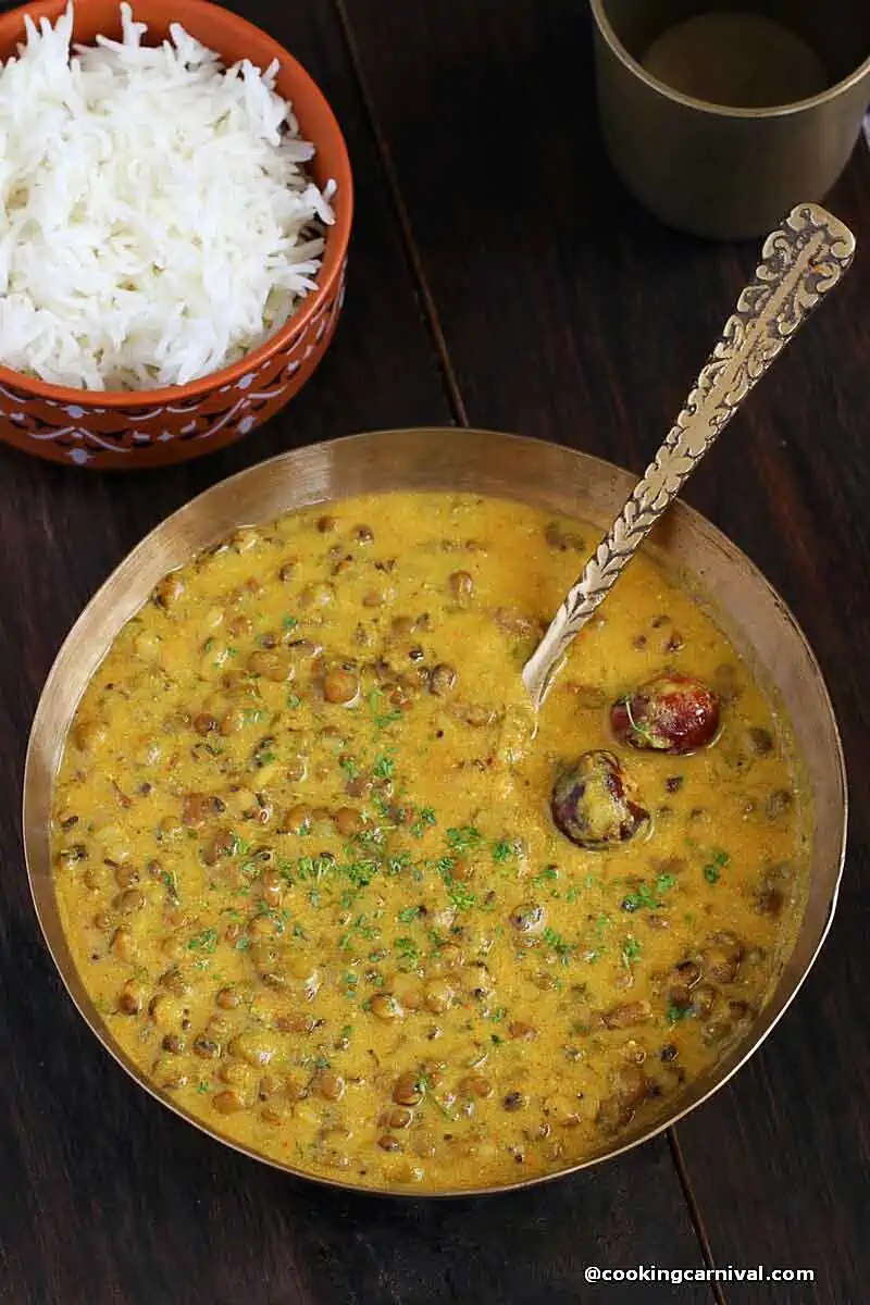 Khatta mag - A Gujarati recipe made with whole moong, yogurt, gram flour and some basil Indian spices, served in a Kansa bowl. Steamed rice on the side.