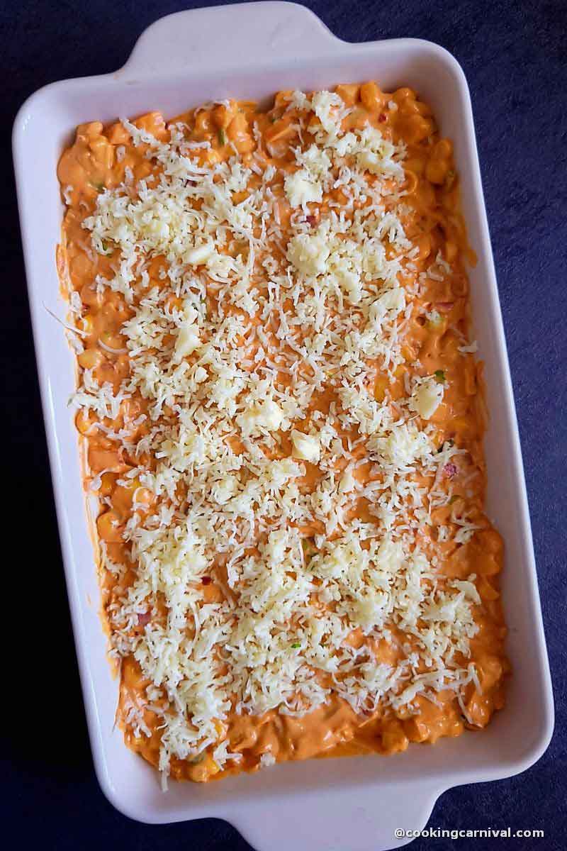 corn dip in baking dip, topped with cheese. Ready to be baked.