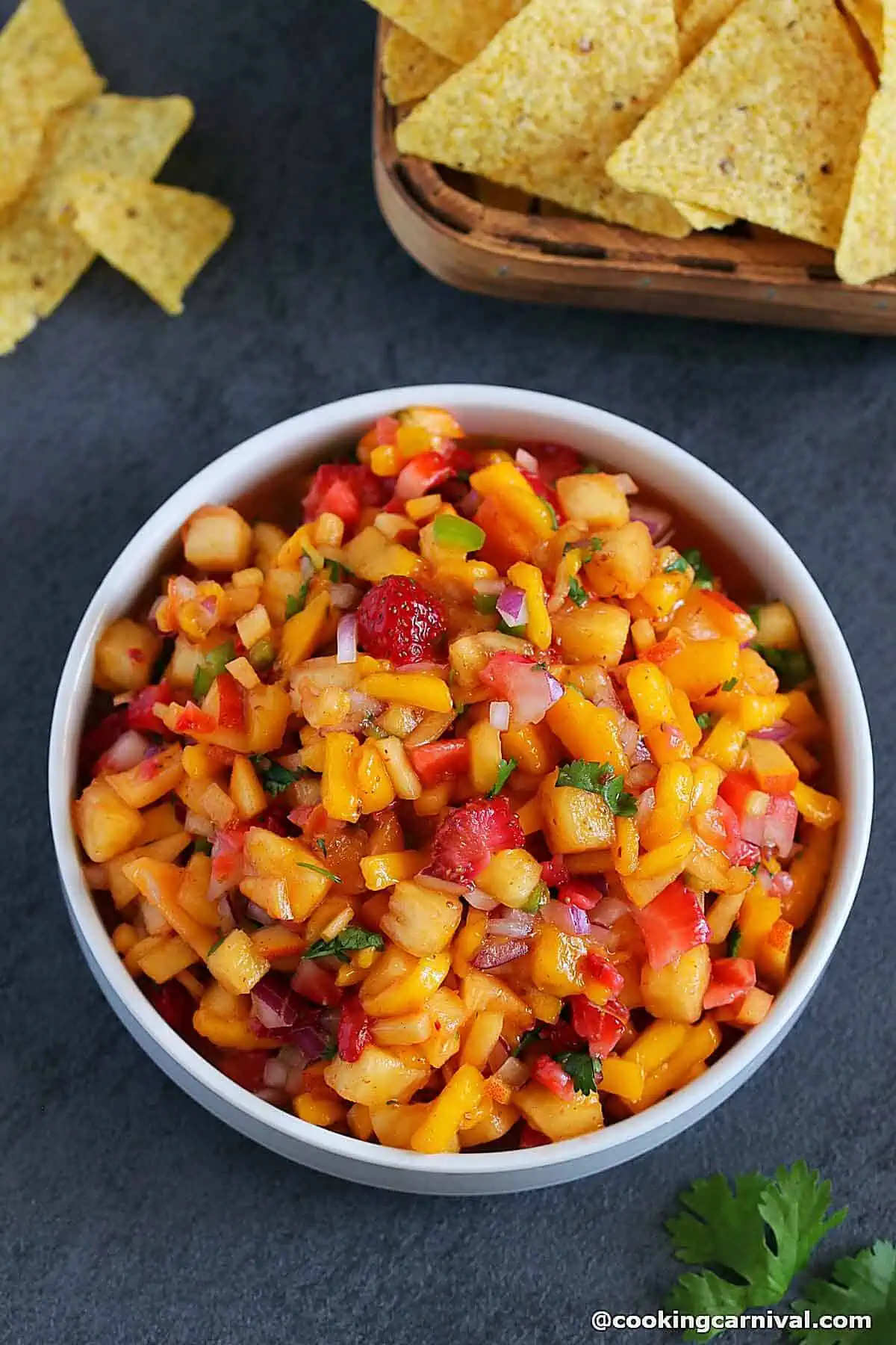 Fruit salsa in a white bowl with corn chips