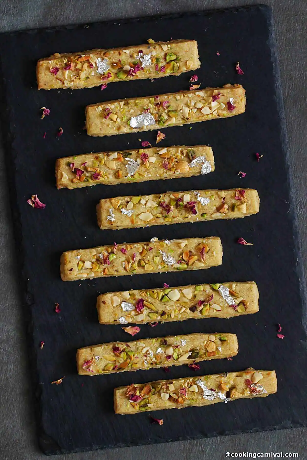 Mawa Gujiya cookie sticks on black cheese board.