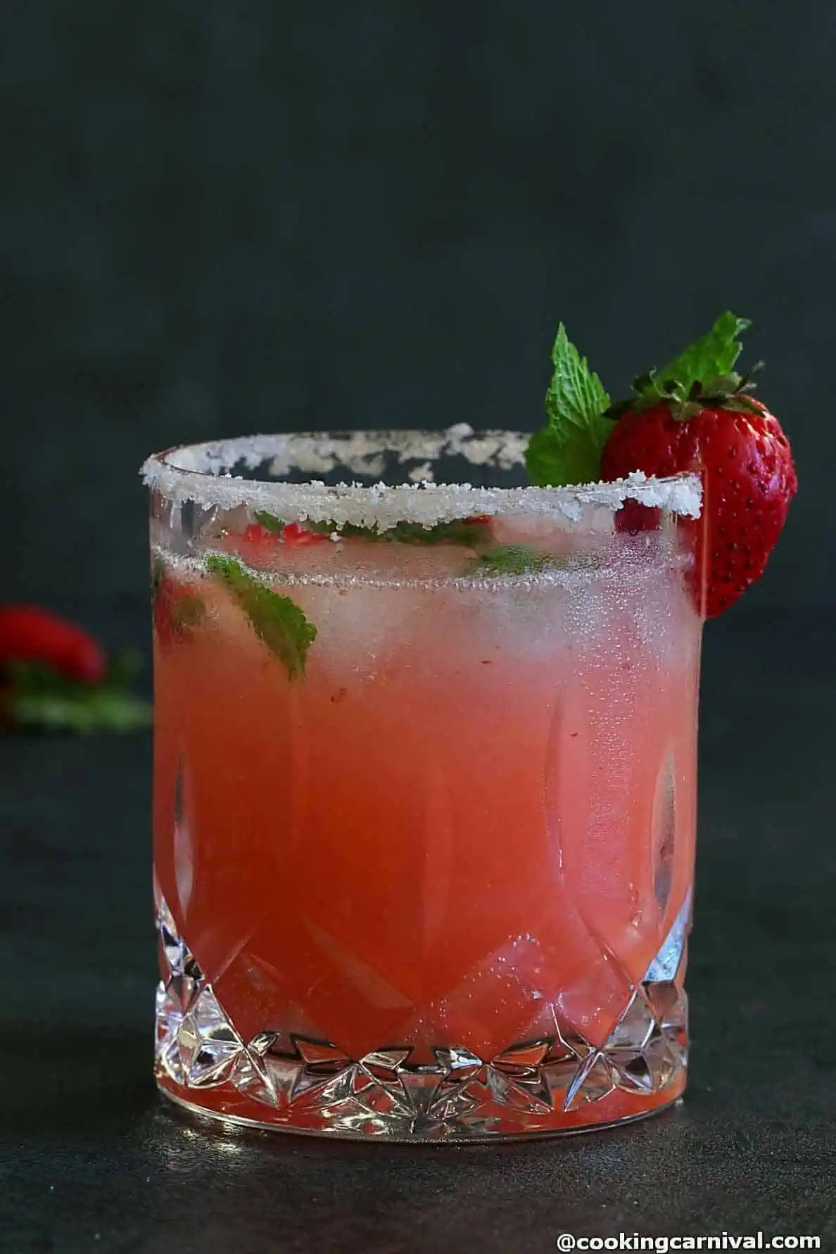No alcohol lychee strawberry fizz in a glass, garnished with mint leaves. 