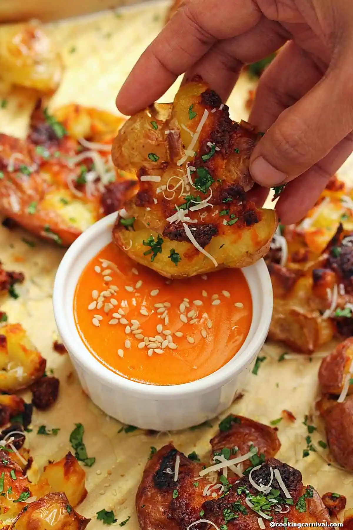 Dipping garlic parmesan smashed potato in creamy gochujang sauce.