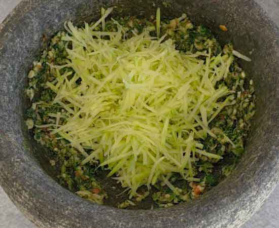 adding grated raw mangos in mirchi ka thecha.