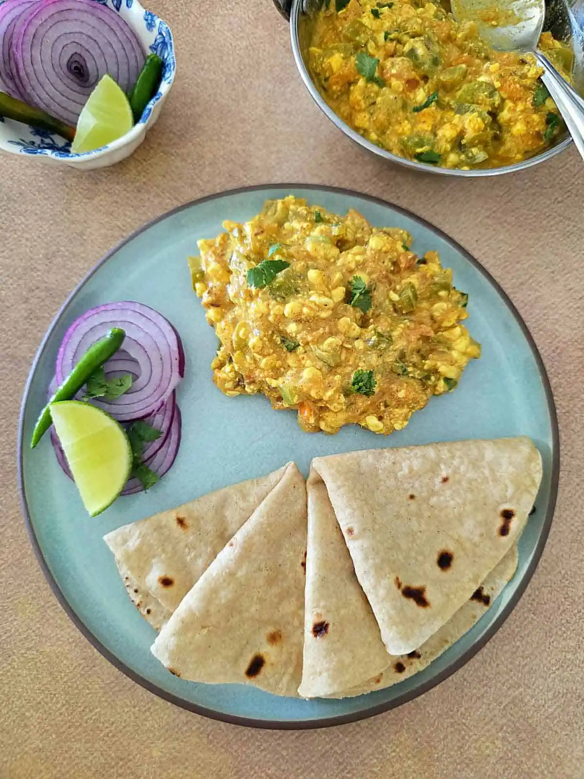 cottacheese curry served with roti and onions on a small plate.