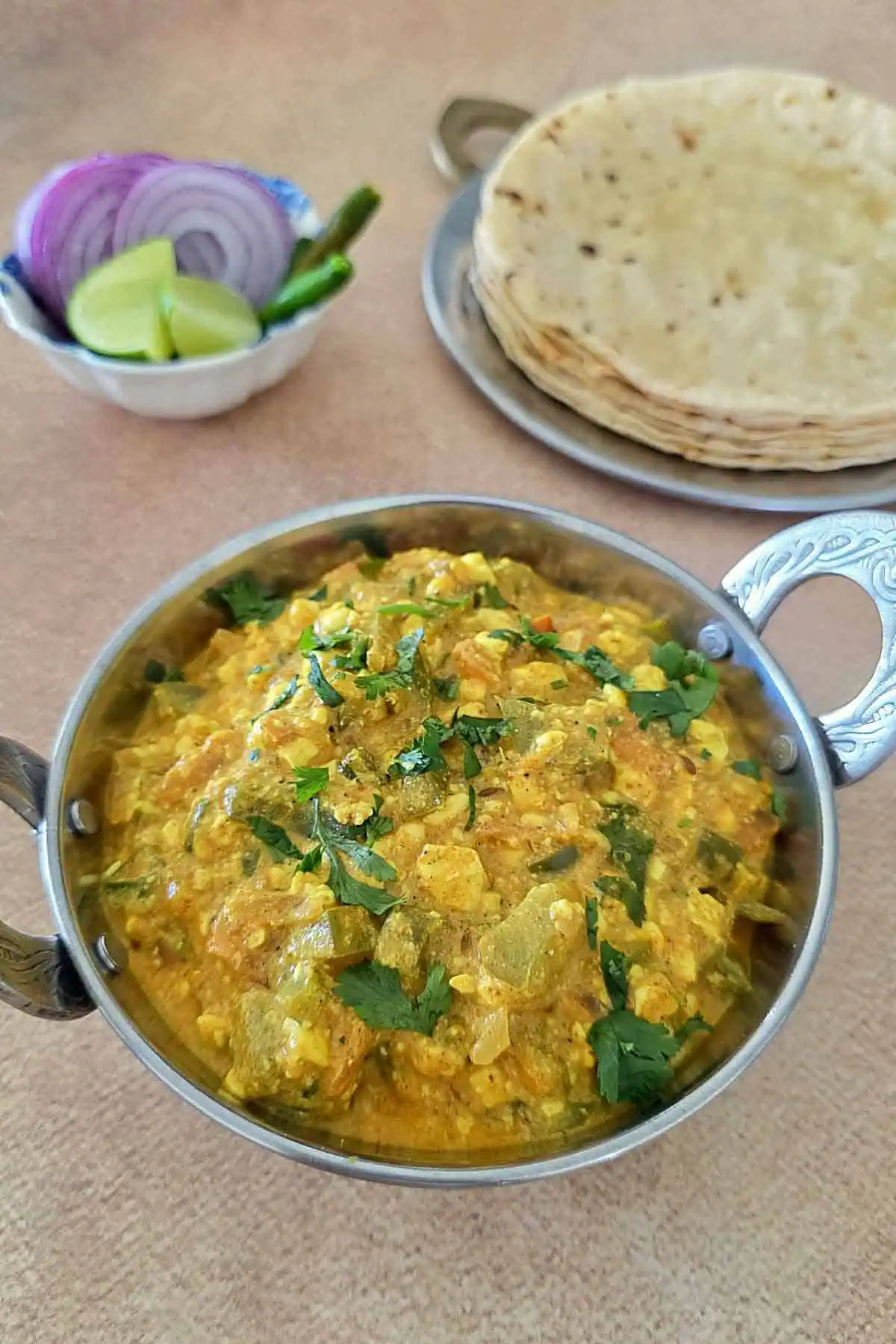 Cottage cheese bhurji i a steel bowl, phulka roti and salad on the sides.